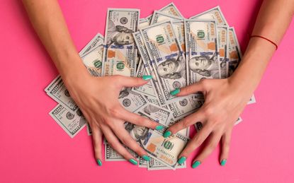 A woman is holding money in her hands. Pink background. Top view copy space. Business. Casino. Wages.