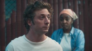 Jeremy Allen White as Carmy looking wide-eyed to the right and Ayo Edebiri as Sydney in the background. 