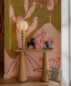 entryway console in front of a graphic mural with a modern lamp on it