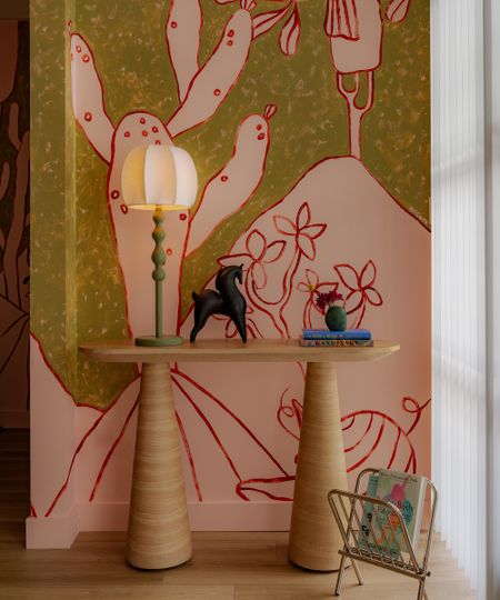 entryway console in front of a graphic mural with a modern lamp on it