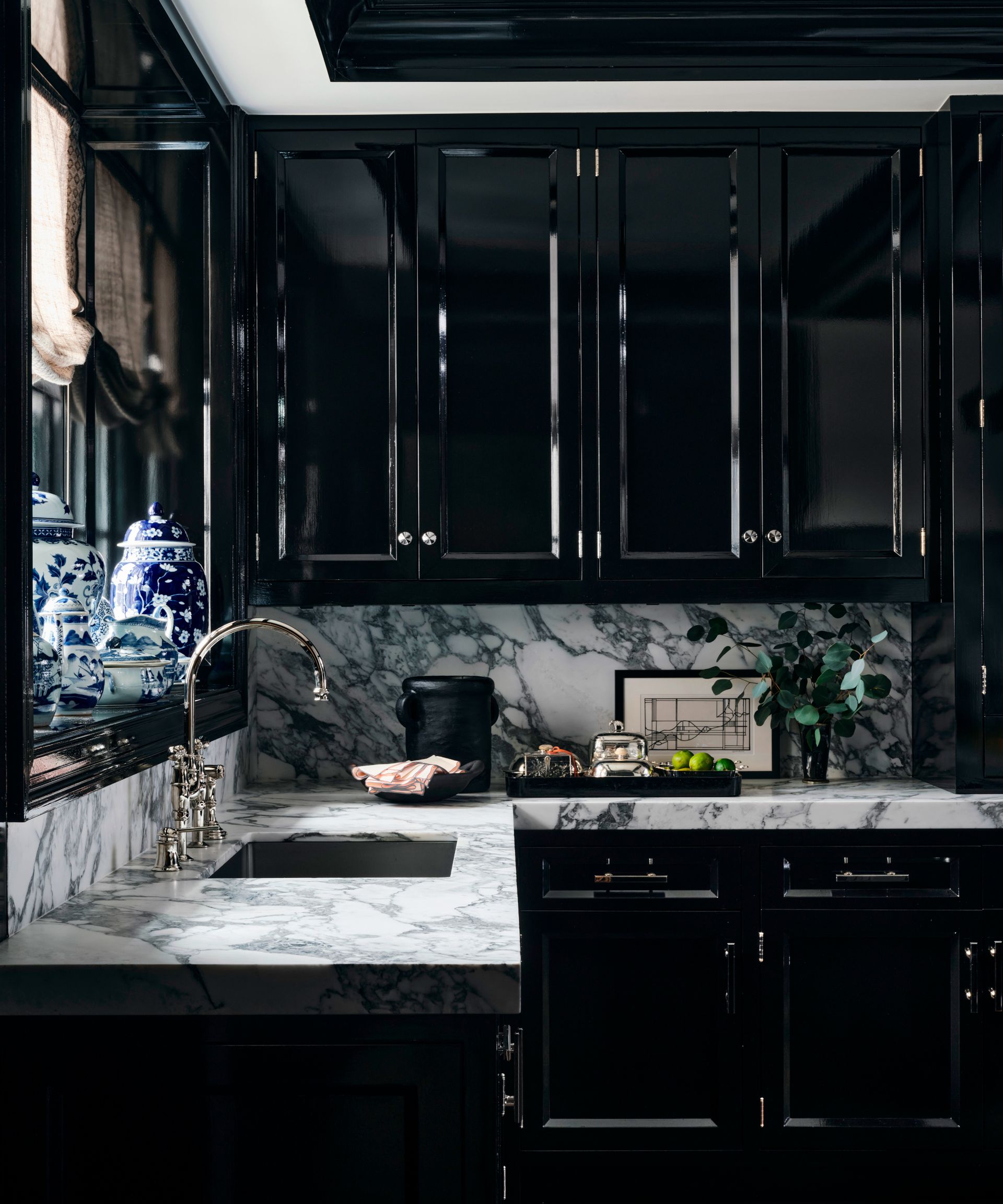black and white kitchen with black cabinets and marble countertop and backsplash