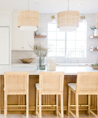 white and wood kitchen with rattan pendants and bar stools, large kitchen island, white countertops, open shelving, tiled wall