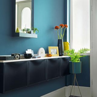 Blue hallway with black storage and mirror