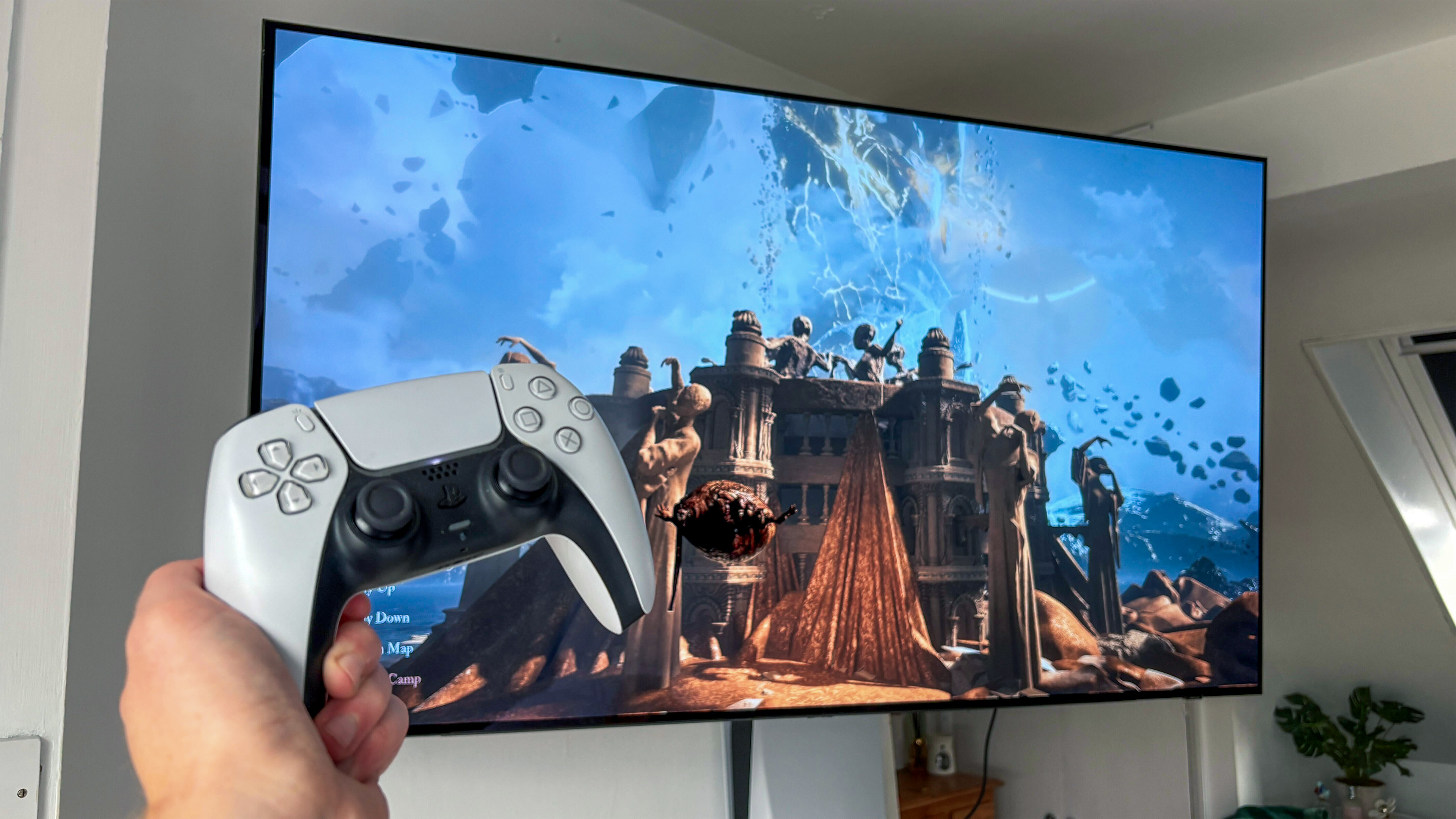Samsung S90D OLED TV behind hand holding PS5 DualSense controller