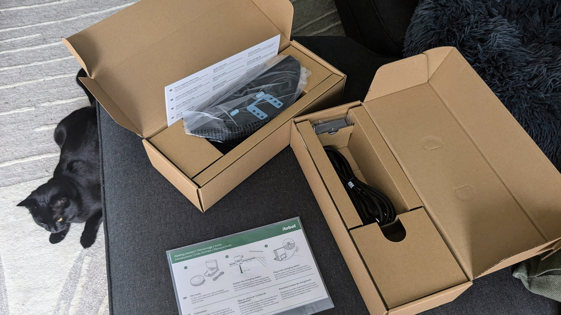 iRobot Roomba Combo j5+ parts in boxes, accompanied by a cat