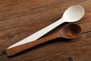 A pair of wooden spoons on a wooden kitchen table.