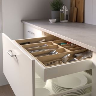 Drawer in a cream gloss kitchen open to show wooden drawer organiser
