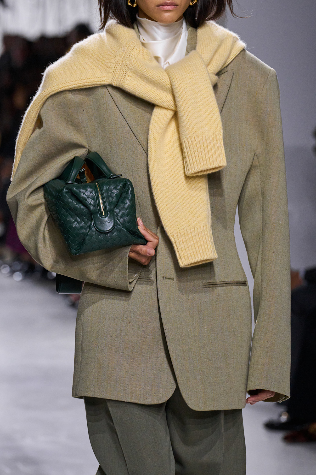 A close-up of a model at the S/S 26 Bottega Veneta show with bits of green or yellow styling.