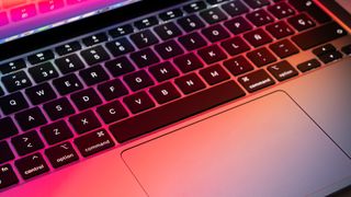 Vinklet bilde av MacBook Pro med rosa skjær på tastaturet fra skjermen 