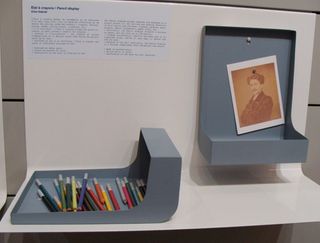 A wall display featuring information and a portrait photo with a collection of pencils.