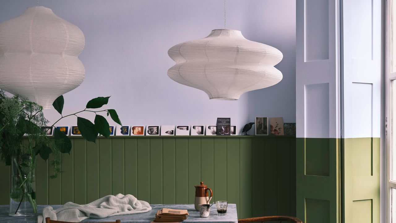 A dining room with a two-tone wall and window shutters in Farrow &amp; Ball&#039;s Sizing and Sap Green