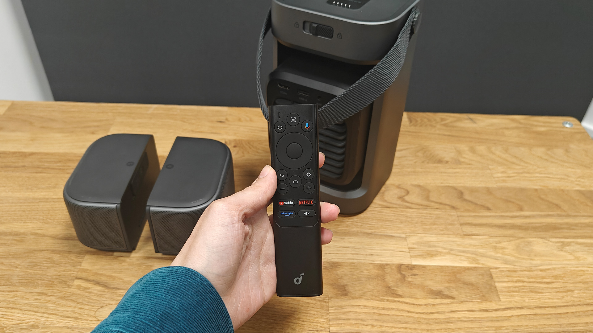 Soundcore Nebula P1 projector with remote control held in hand above