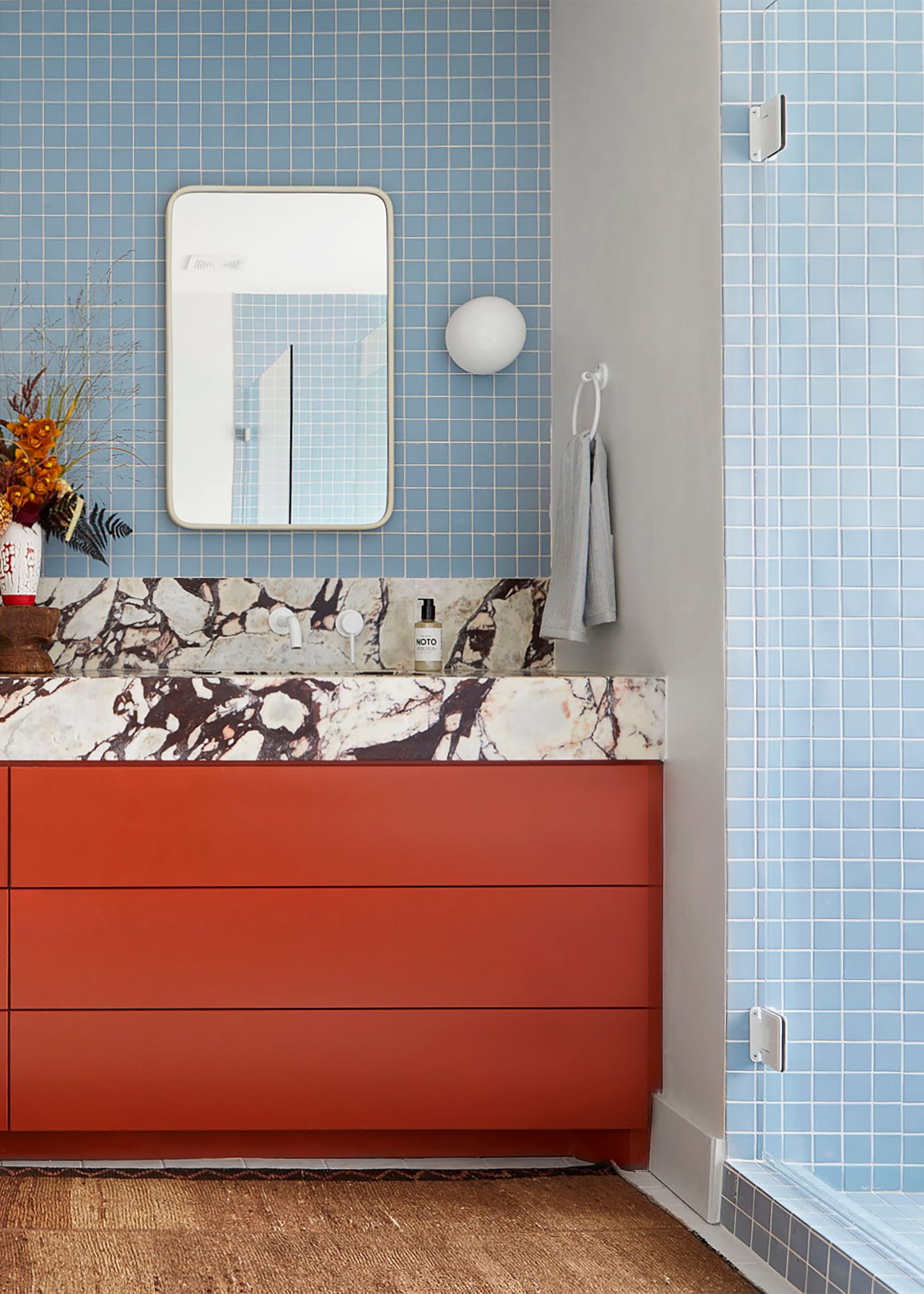 Baby blue bathroom tiles with red drawers and marbled countertops