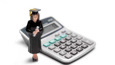 Small female graduate cake topper standing next to a calculator