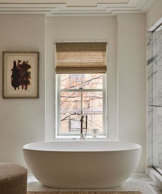 A neutral bathroom with a marble tiles shower area, a free-standing bath, and soft furnishings in natural colors and textures