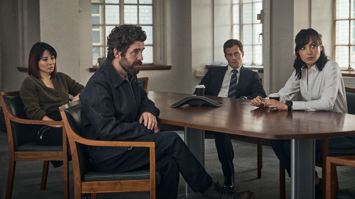 Four members of the Heart of Stone cast sitting at a table: Yang (Jing Lusi), Bailey (Paul Ready), Parker (Jamie Dornan) and Rachel Stone (Gal Gadot), L-R.