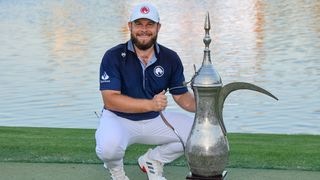 Tyrrell Hatton poses next to the 2025 Hero Dubai Desert Classic trophy