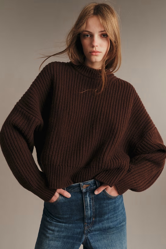 A model wearing a brown sweater.