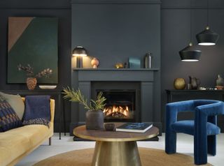 black living room with fireplace, yellow sofa, blue modern armchair, round gold coffee table