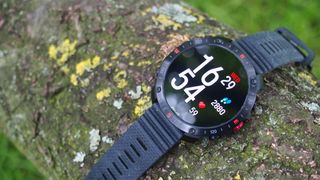 Polar Grit X2 Pro watch on a log showing clock face and step count