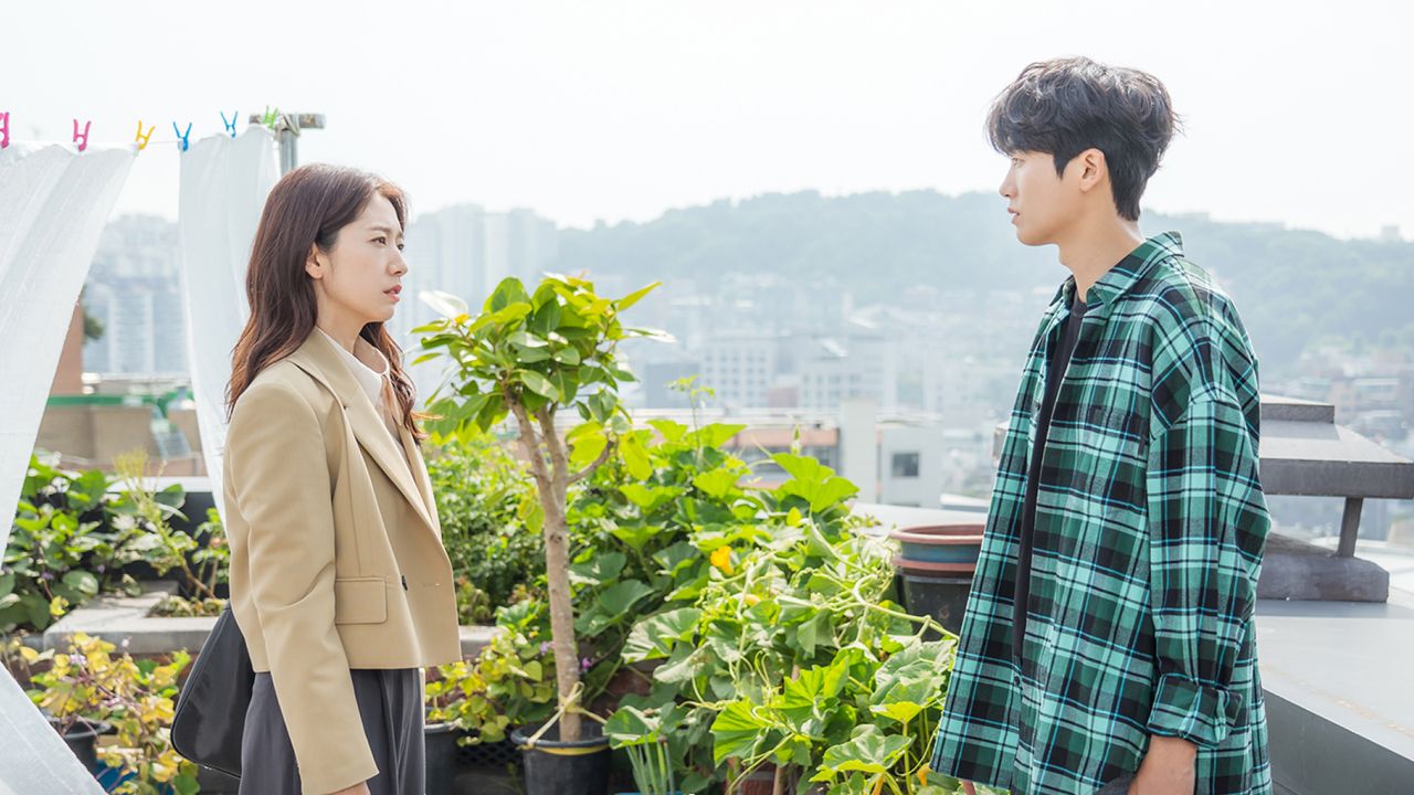 a woman and a man look at each other while standing on a seoul rooftop