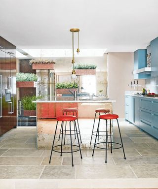 Mirrored island with bright red stools and blue painted cabinetry