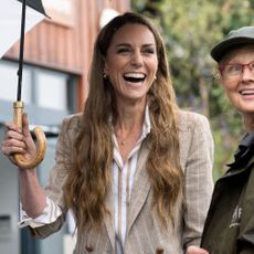 Kate Middleton wears a brown striped blazer with brown pants and white sneakers