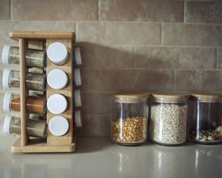A kitchen with assortment of spice canisters in spice rack on counter