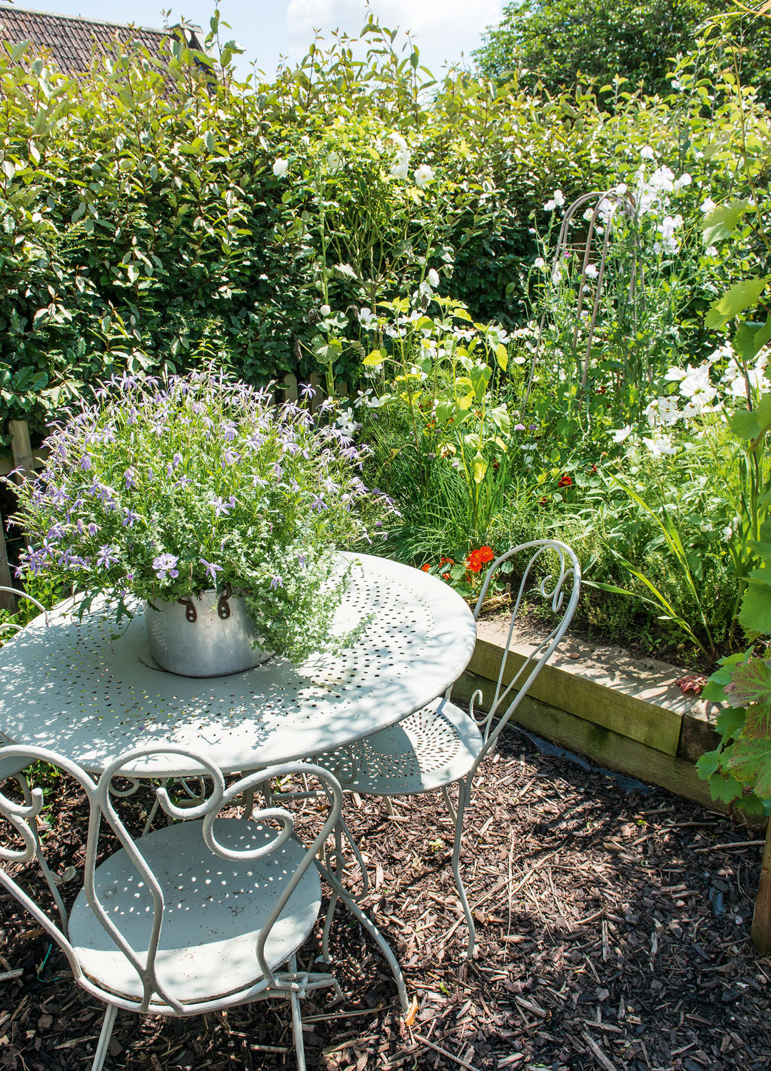 country garden with raised flower beds and iron bistro table and chairs