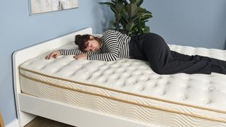 Tom's Guide Sleep Features Editor lies on her side on the Saatva Classic mattress during a testing panel review session at our sleep studio