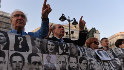 Protesters hold a banner with pictures of missing people from the Franco era