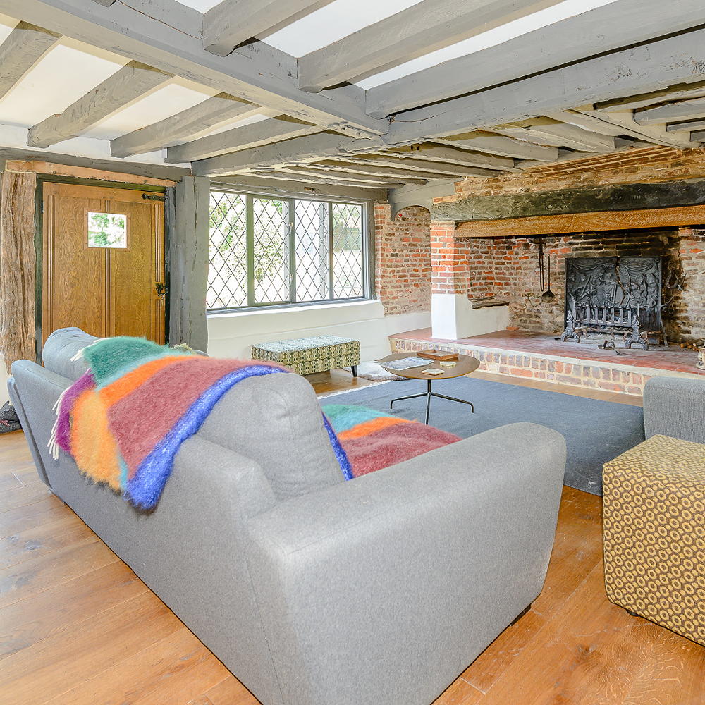Lounge with blue couch, fireplace, wooden floor, wooden door and wooden roof.