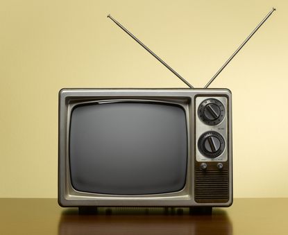 Vintage TV with antenna on yellow background