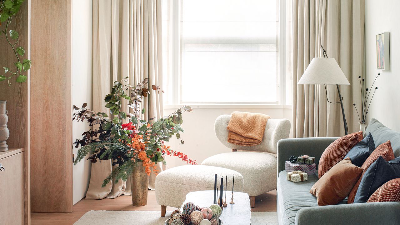 a living room with a blue sofa and cream walls and curtains