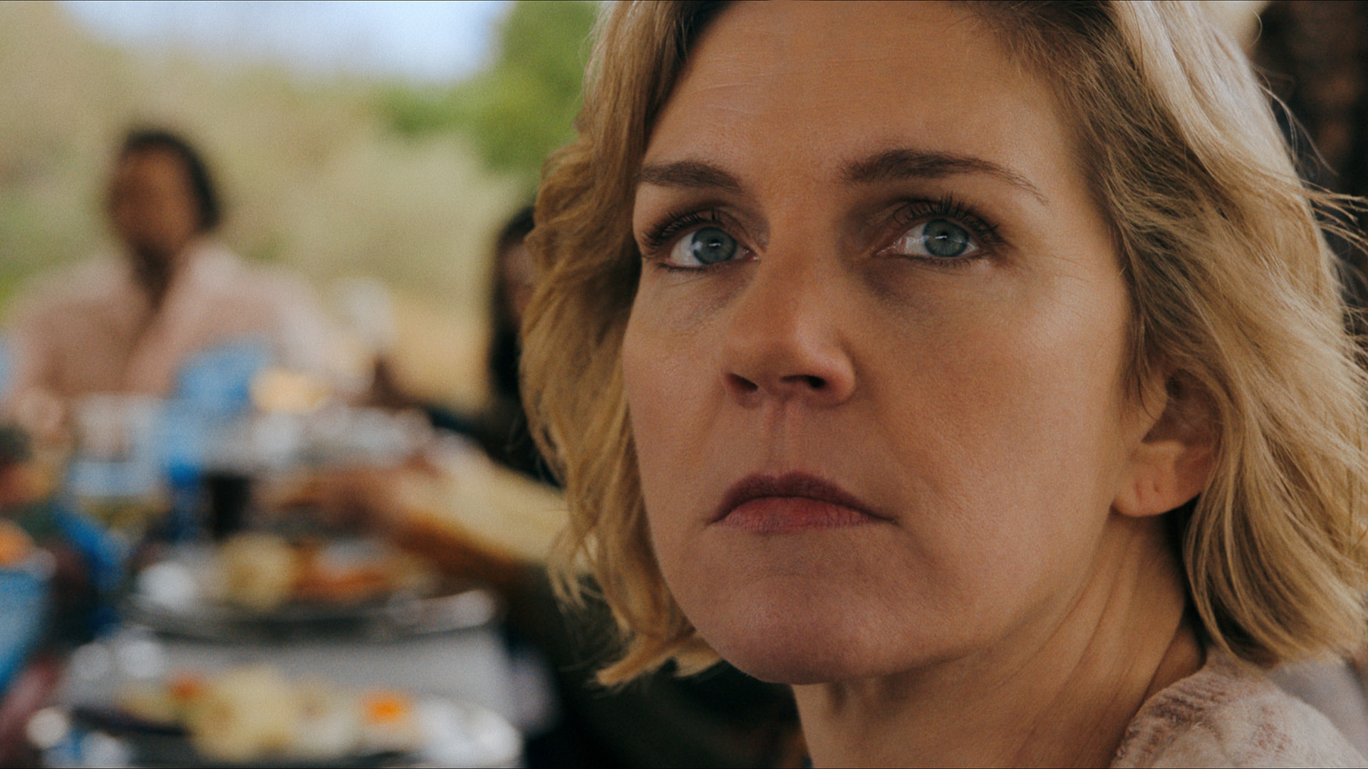 a blonde-haired woman turns to look at the sky