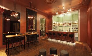 Alternative view of the bar, with dark wood floor, copper highlights, and framed mirrors