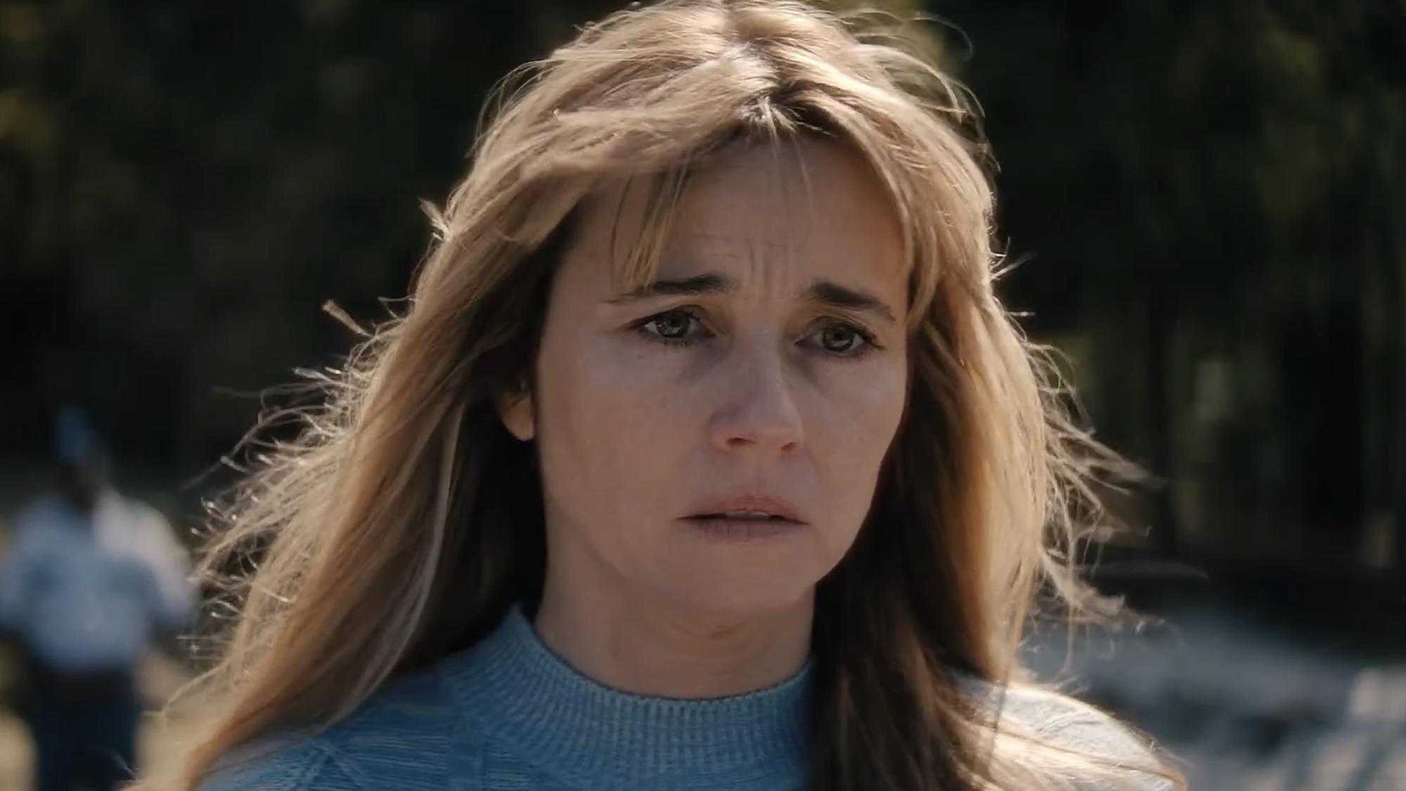 Pamela Voorhees looking out at lake with sad expression with an EMT worker in the background in Crystal Lake Season 1