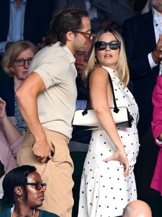 Margot Robbie and her husband in the stands at Wimbledon where she wears a polka dot dress and an east west bag