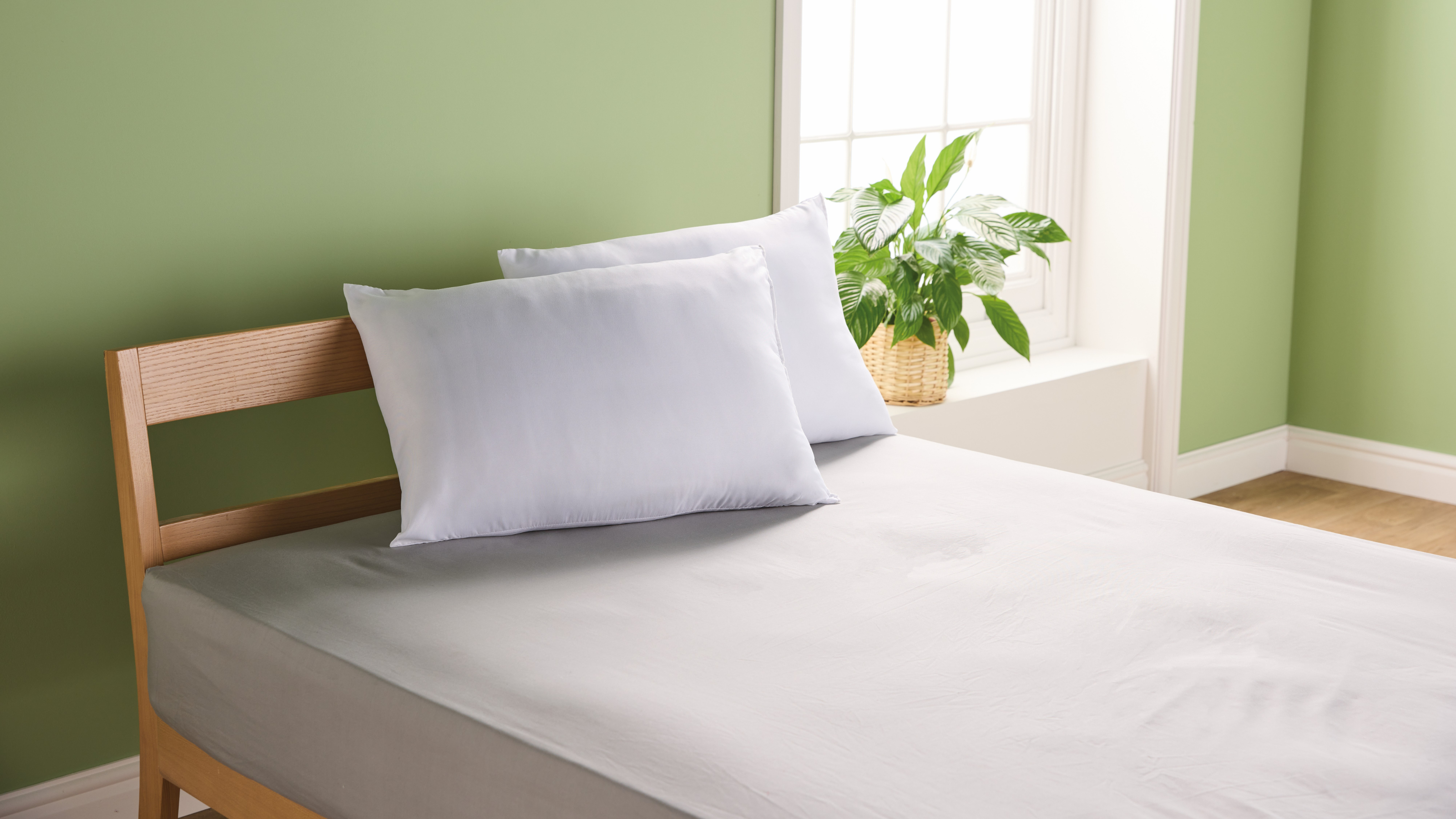 Aldi cooling pillows on a double bed in a green bedroom.
