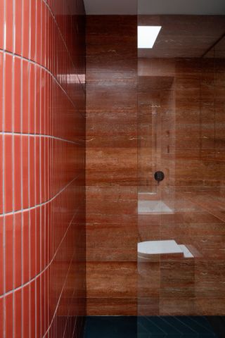 A red bathroom with red tiled walls and contrasting stone shower