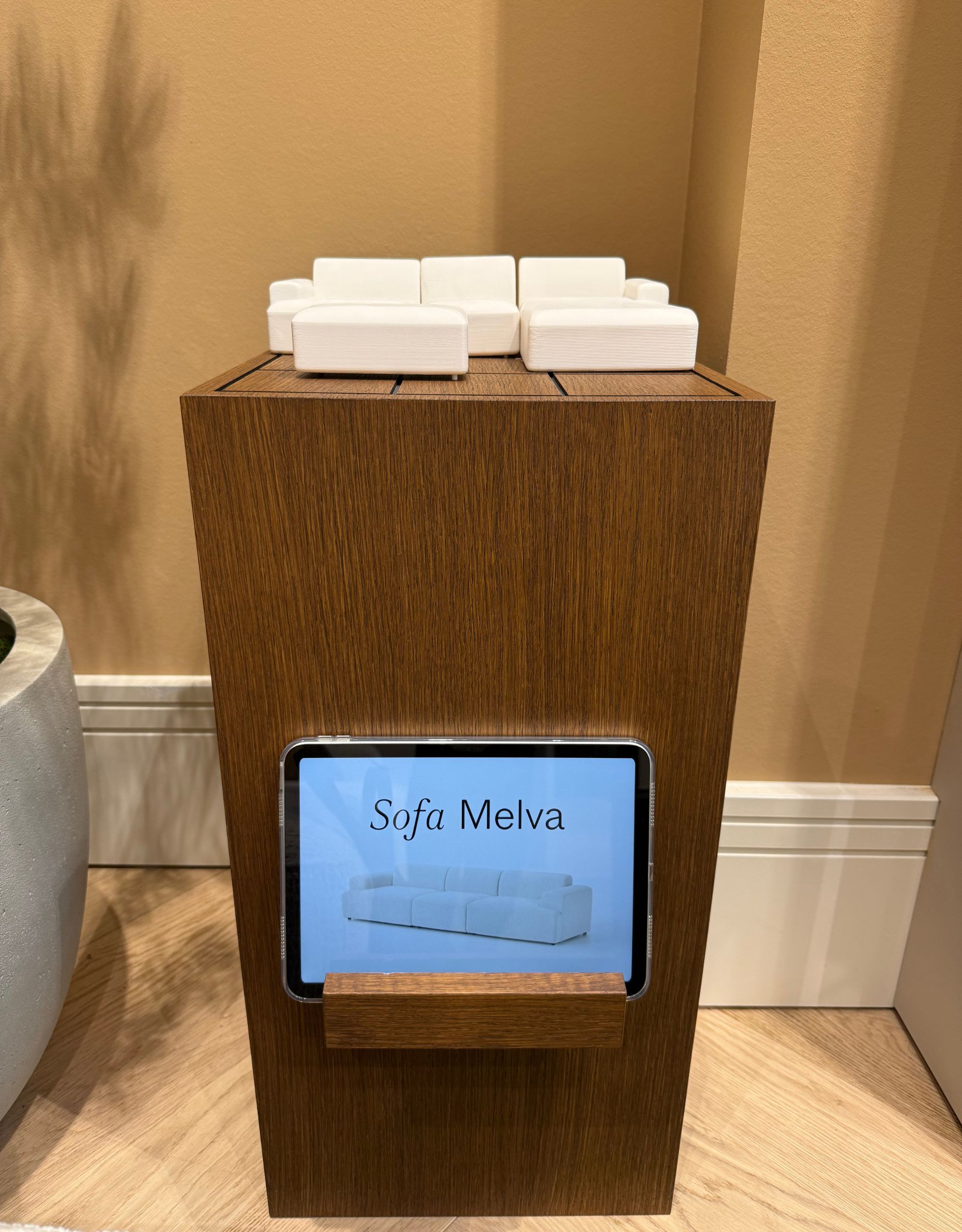 A plinth with an ipad holder on the front and a mini modular sofa set in white on top