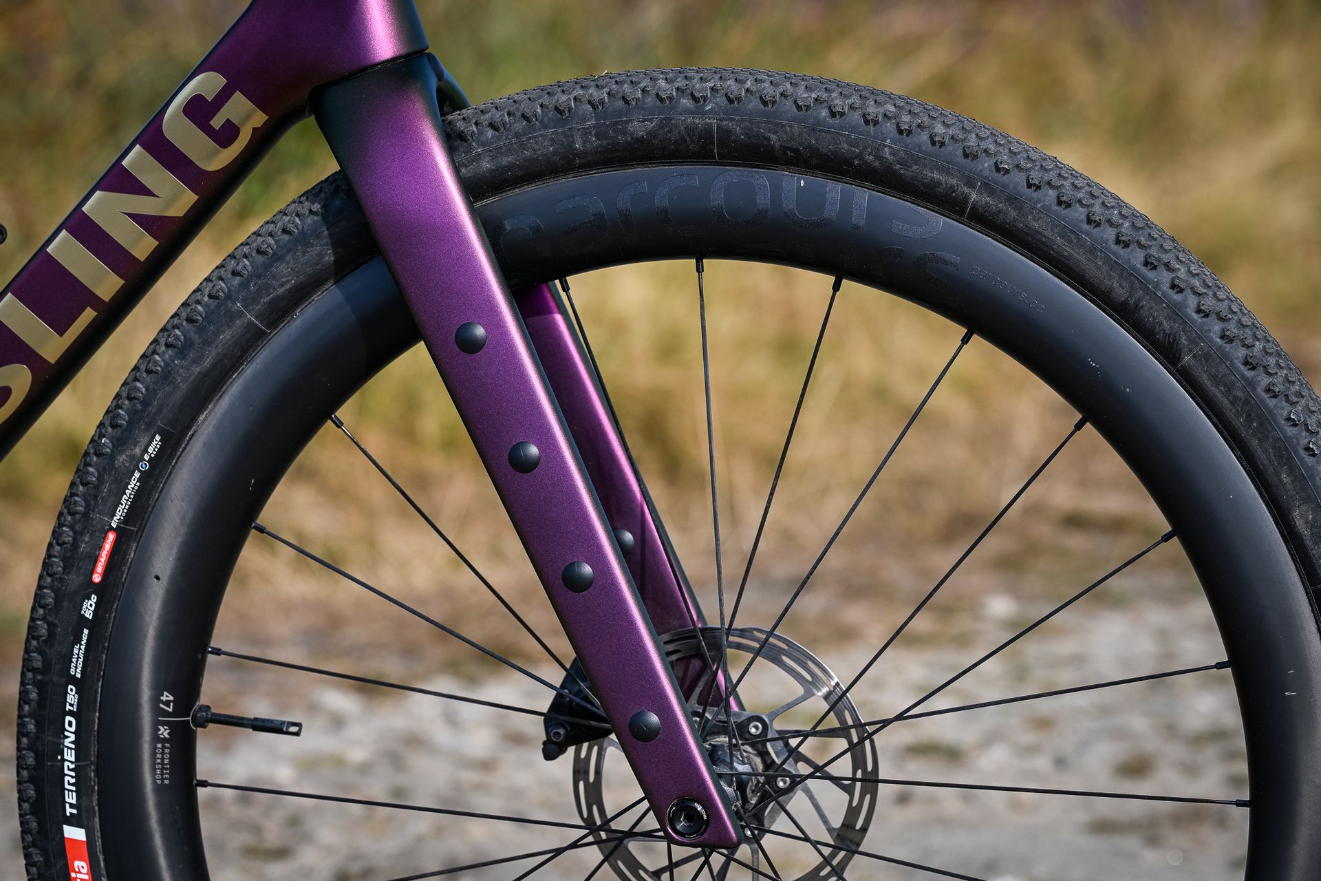 side-on close-up of the purple forks and front wheel on a gravel bike