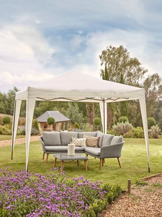 Large white pop up gazebo covers modern outdoor dining area on large backyard lawn