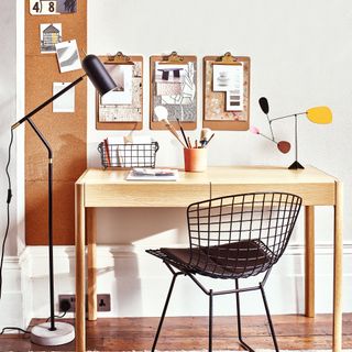 Wooden desk with metal desk chair and clipboards on wall
