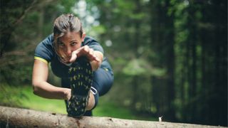 Woman athlete stretching in the forest after running