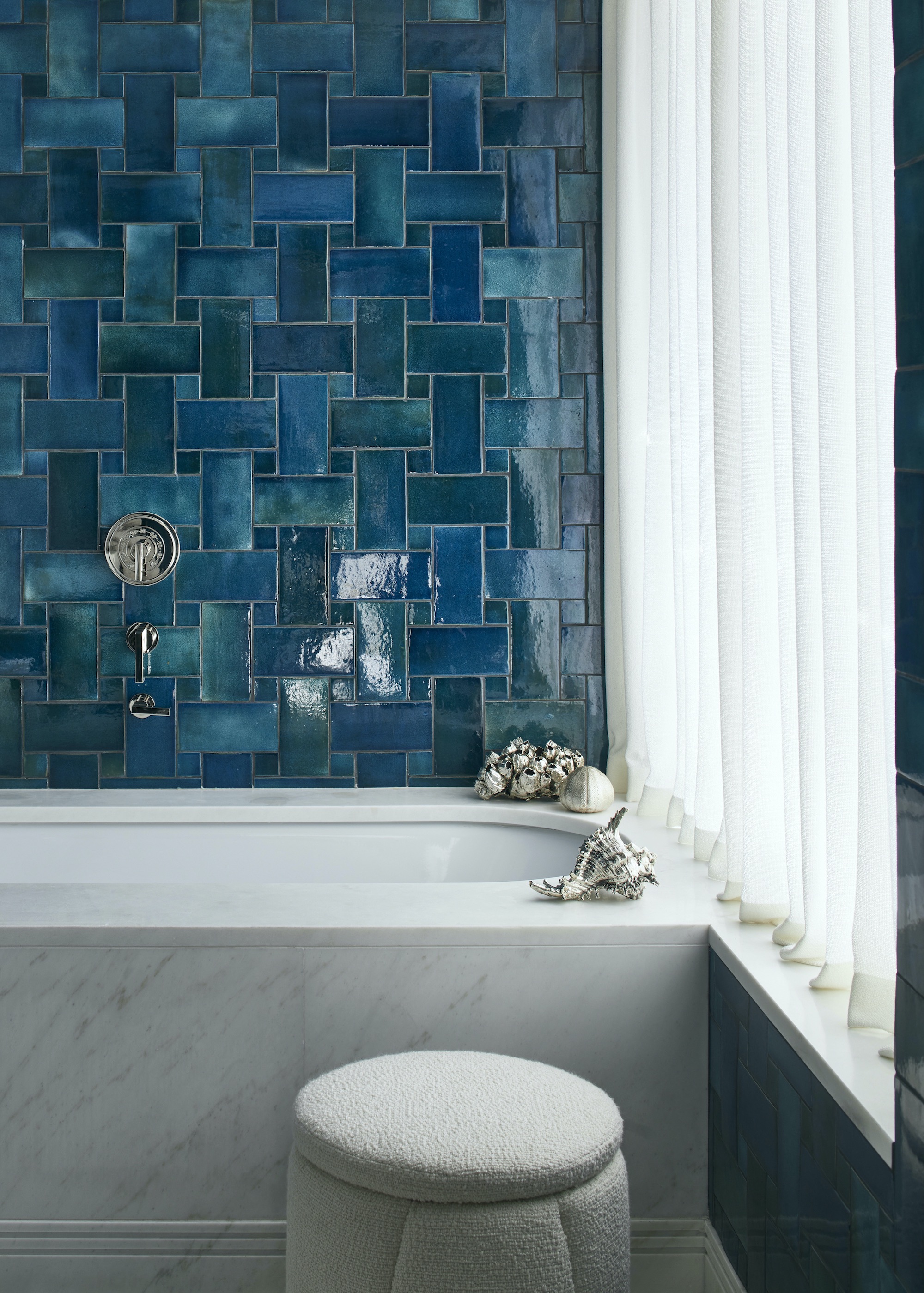 bathroom with blue zellige tiles and marble bath in the space. There is also a stool beside the bathtub