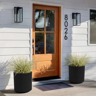 Two black decorative pots flanking an orange front door 