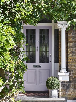 Front door painted in lavender surrounded by wisteria