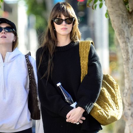 Dakota wears cat-eye sunglasses, a black sweater, and a bottega veneta oversize bag.