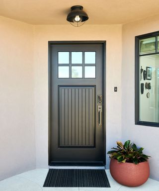 black front door with small glass windows and an overhead light
